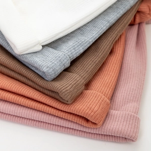 Gros plan d'une pile de bonnets tricotés pour bébé en plusieurs couleurs et textures
