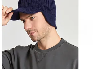 Detail view of navy blue knitted visor beanie with ear flaps and metal JEANS emblem