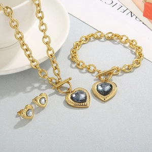 Detail of gold chain jewelry set with heart-shaped dark grey faceted crystal pendants