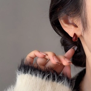 Gros plan de la boucle d'oreille goutte rouge foncé portée sur le mannequin