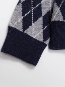 Detail of argyle knit sweater showing ribbed cuffs and navy grey diamond pattern texture