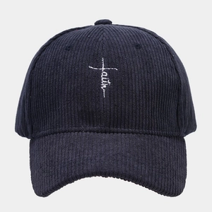 Close-up of white faith cross embroidery on navy blue corduroy baseball cap texture