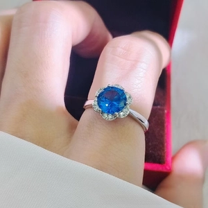 Close-up of flower-shaped ring with a large blue centerpiece and pavé diamond halo