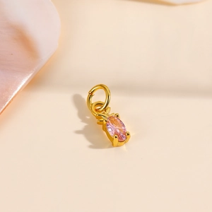 Detail of 18k gold pineapple pendant featuring pink cubic zirconia and polished finish