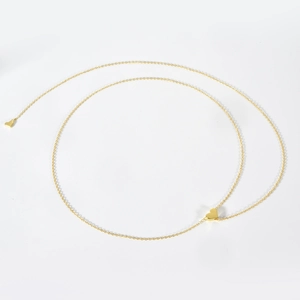 Detail of a minimalist gold chain necklace featuring a polished heart pendant on white background