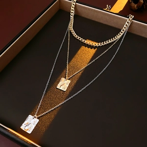 Detail of multi-layer metallic necklace with hammered square pendants in gold and silver