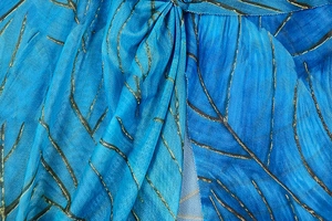 Detail of blue mesh fabric featuring artistic gold and black leaf vein vein patterns