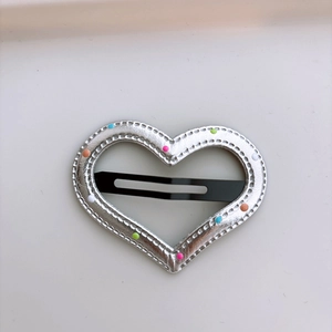 Detailed view of heart-shaped silver hair clip featuring colorful polka dots and stitching