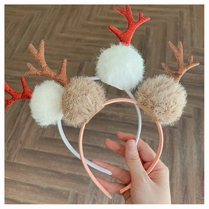 Detail of glittery Christmas antlers headbands with soft pom-poms in red and brown colors
