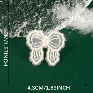 Detail of cream lace bow patch showing dimensions 4cm x 4.3cm on dark green background