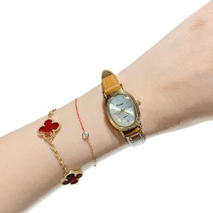 Elegant gold oval quartz watch for women with brown leather strap worn on wrist