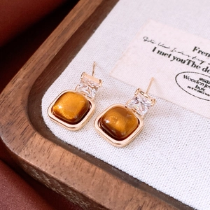 Détail de boucles d'oreilles plaquées or 18 carats avec œil de tigre et cristaux