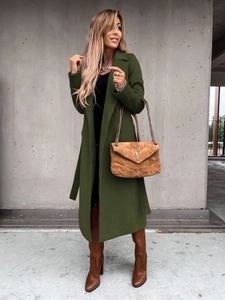 Detailed close-up of dark green long wool coat with classic lapel and matching waist belt