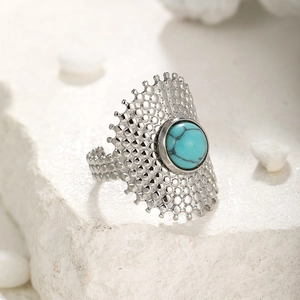 Macro shot of silver ring with turquoise stone and hollow dot patterns on stone texture
