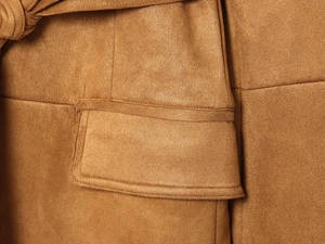 Dettaglio della giacca scamosciata color cammello con cuciture e nodo in vita elegante