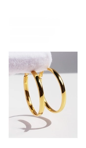 Detailed view of large polished golden hoop earrings with glossy reflective finish