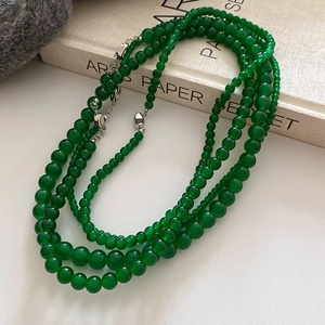 Vue détaillée du collier de perles vertes multicouches avec fermoir argenté sur livre