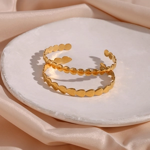Detailed shot of gold-plated heart and round disc adjustable open bangles on silk