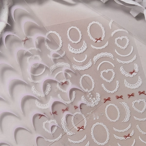 Macro shot of ultra-thin lace nail stickers with white heart frames and red bows