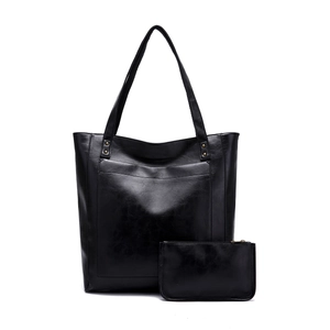 Détail de la texture en cuir ciré noir du sac cabas avec rivets métalliques et porte-monnaie