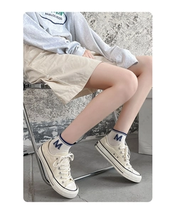 Close-up of low-top canvas sneakers paired with blue striped cotton ankle socks