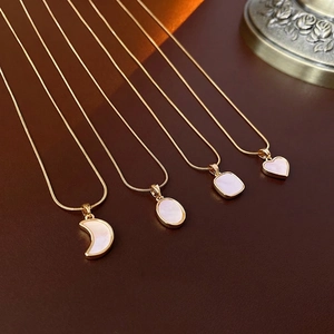 Colliers en acier titane avec pendentifs nacre sur surface en cuir marron élégante