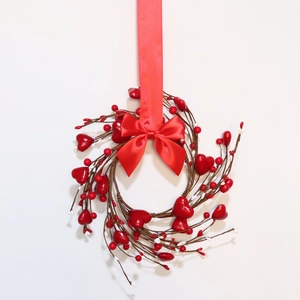 Close-up of heart berry wreath with red satin bow on rustic brown twig base decoration