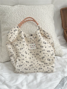 Detail of floral canvas tote featuring woven rope handles and secure magnetic closure
