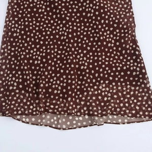 Detail of coffee brown polka dot chiffon dress featuring lightweight fabric and hemline