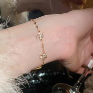Nahaufnahme eines Goldketten-Armbands mit zwei glänzenden Zirkonia-Kreuzanhängern