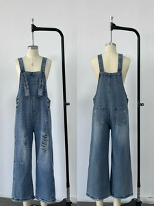 Detailed view of vintage-style distressed denim overalls with ripped knees and wide leg cut