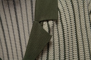 Macro detail of high-density knit polo texture with olive green and beige stripes