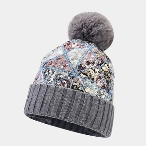 Detailed view of colorful sequins on knitted hat with a fluffy grey faux fur pompom top
