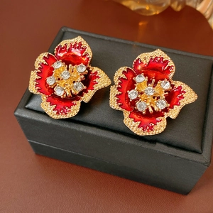 Macro detail of vintage floral earrings with red enamel and white crystal accents