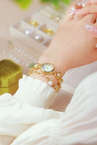 Detailed shot of a gold women's watch with pearl metal strap and round quartz dial