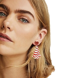 Festive acrylic Christmas tree earrings featuring red hearts on a female model