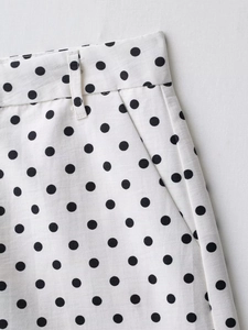 Dettaglio dei pantaloncini bianchi a pois con passanti per cintura e tasche laterali