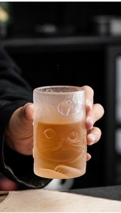 Detail of frosted glass cat relief tea cup with hand-held grip showing cozy texture