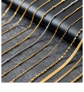 Detailed view of various gold and silver titanium steel chains on a dark stone surface