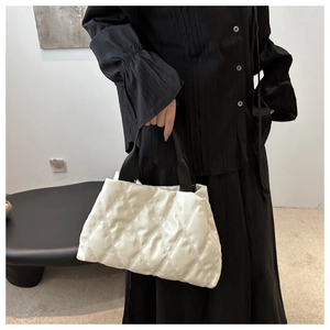 Close-up of a white quilted handbag featuring a soft puffy texture and black strap handles