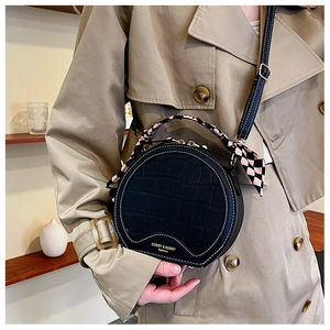 Detail of black crocodile texture PU leather handbag with decorative pink plaid silk scarf