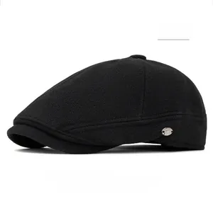 Detailed texture of a black wool flat cap with a silver metallic logo plate on the side