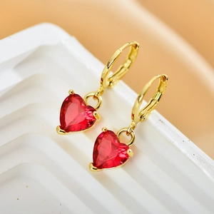 Macro shot of gold hoop earrings with red heart shaped zircon charms for women