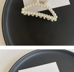 Detailed view of elegant pearl hair claw clip with golden metal spring and white pearls