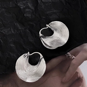 Silver textured hoop earrings with concentric spiral patterns on a dark backdrop