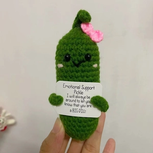 Close-up of hand-knitted green emotional support pickle with pink bow and card