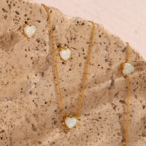 Detail view of heart-shaped opal jewelry set on a natural stone base