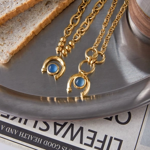Detailed macro view of 18K gold stainless steel bracelets with blue resin charms on metal tray
