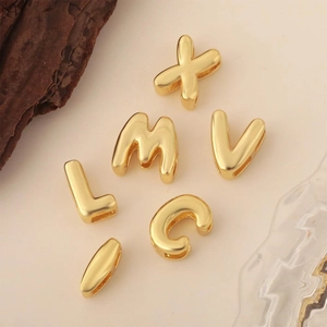 Dettaglio di ciondoli a lettera 3D placcati oro 18K per creazione gioielli DIY