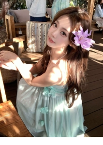 Detailed view of the 3D purple fabric flower hair clip worn by a model in sunlight